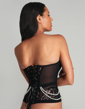 Woman wearing a black lace corset against a gray background